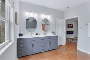 A bathroom with a large vanity, two mirrors, and a sink. There are lights above the mirrors and a towel rack.