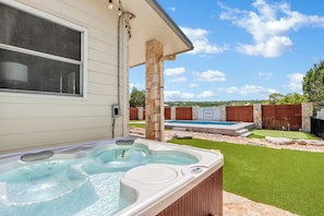 A hot tub in a backyard with a pool, artificial grass, and a wooden fence. - Artista I 2/2 with New Pool, Hot tub,  Pool Table (Wimberley)