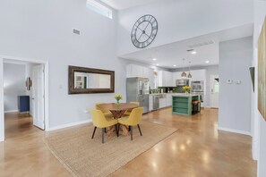 A spacious kitchen with modern appliances, a dining area with yellow chairs, and a large wall clock. - Artista I 2/2 with New Pool, Hot tub,  Pool Table (Wimberley)