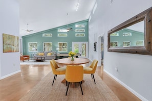 A dining area with a round table, yellow chairs, and a vase of flowers.