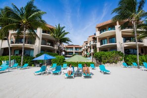A resort with multiple-story buildings, a sandy beach, and palm trees.