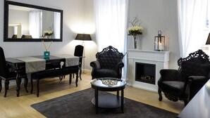 A living room with a fireplace, a dining area with a table and chairs, and a large mirror on the wall. - Belsiana Apartment - Two Bedroom Apartment, Sleeps 6 (Roma)