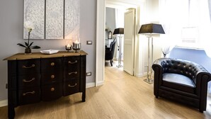 A room with a dark wooden dresser, a black leather sofa, and a white door leading to another room. - Belsiana Apartment - Two Bedroom Apartment, Sleeps 6 (Roma)