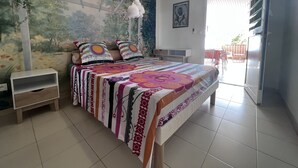 A bedroom with a bed, a nightstand, a wall mural, a ceiling fan, and a sliding door to a balcony.