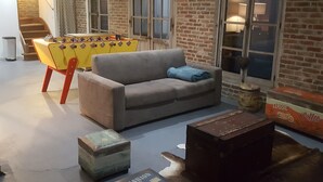 A cozy room with a sofa, a foosball table, and a clock on the wall.