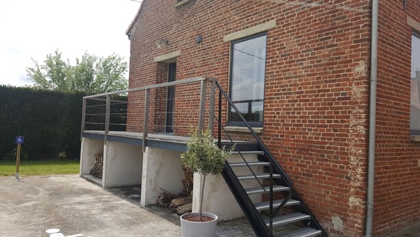 A brick building with a metal staircase leading to a landing.
