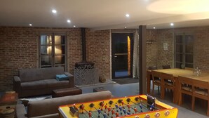 A cozy living room with a foosball table, a sofa, and a dining area with a table and chairs.