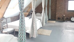 A bedroom with a sloped ceiling, a brick wall, and a bed with a canopy.