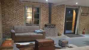 A cozy living room with a brick wall, a sofa, a small table, and a fireplace.