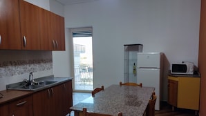Una cocina compacta con gabinetes de madera, encimera de granito, microondas integrado y una mesa de comedor con sillas.