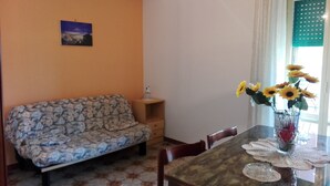 Un comedor con una mesa, sillas, un sofá y un florero con flores.