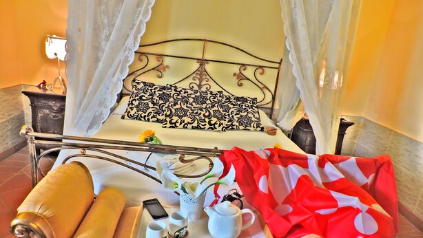 A bed with a metal frame, a decorative pillow, and a tray with a cup, saucer, candles, and a smartphone. - Apartment in VILLA " ARIALE " (Vicopisano)