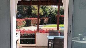 An outdoor patio with a wooden deck, a covered seating area, and a view of a landscaped garden with red foliage. - Lavender villa is set in our beautiful landscaped gardens next to the pool.  (Tsikalaria)