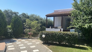 A garden pathway leading to a building with a tiled roof and outdoor seating. - Lavender villa is set in our beautiful landscaped gardens next to the pool.  (Tsikalaria)