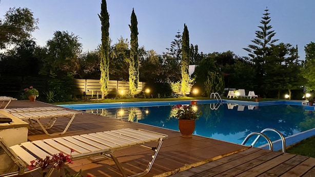 A swimming pool with lounge chairs and a wooden deck. - Lavender villa is set in our beautiful landscaped gardens next to the pool.  (Tsikalaria)