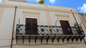 A building with a balcony, a window, and a plant on the roof.