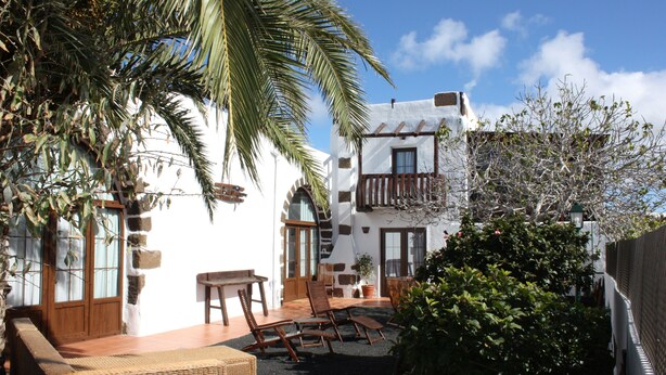 A courtyard with a patio area, wicker furniture, and a stone wall. - Casa Rural La Molina large apartment in an old motor mill from 1912 (Maguez  -Lanzarote)