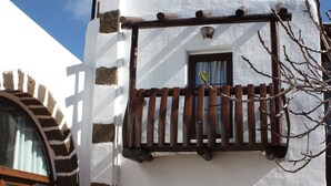 A building with a white facade, brown accents, a wooden balcony, and a potted plant. - Casa Rural La Molina large apartment in an old motor mill from 1912 (Maguez  -Lanzarote)