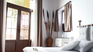 A bedroom with a bed, a dresser, a mirror, and a window with curtains. - Casa Rural La Molina large apartment in an old motor mill from 1912 (Maguez  -Lanzarote)