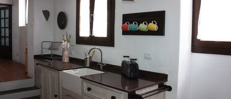 A kitchen with a double sink, a toaster, and a window with curtains.