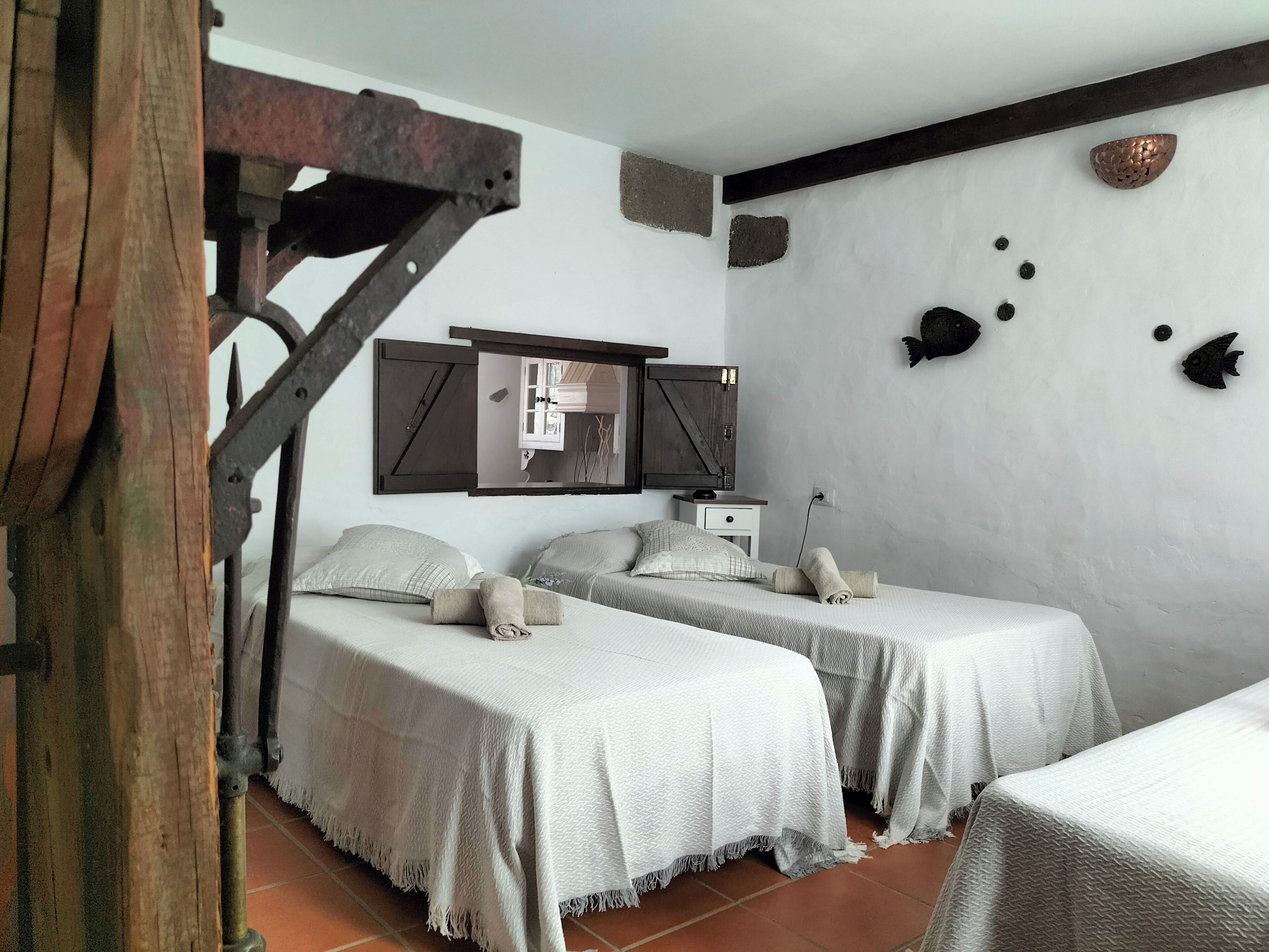 Quarto com duas camas, escada de madeira, espelho e parede decorada com peixes.