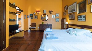 A hotel room with a bed, a TV, a chair, a dresser, and artwork on the walls. - Chalet La Alpispa with private pool in Las Palmas. (Las Palmas de Gran Canaria)