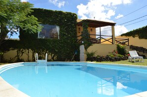 Una piscina con cubierta de madera y una silla de descanso.