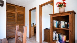 Un couloir avec des portes en bois, un miroir et une bibliothèque remplie de livres.