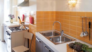 A modern kitchen with a gas stove, a sink, and a chair.