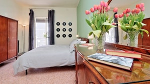 A bedroom with a bed, a dresser, a mirror, and a window with curtains.