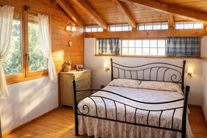Une chambre confortable avec un plafond en bois, un cadre de lit en métal, une commode en bois et une fenêtre avec des rideaux.