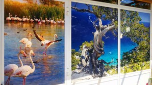 A room with a large window displaying a painting of flamingos and a tree. - Comfortable and bright apartment with terrace just 300 meters from the sea (Quartu Sant'Elena)