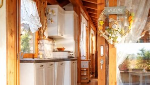 A wooden cabin interior with a kitchen area, wooden stairs, and a view of the outdoors. - Comfortable and bright apartment with terrace just 300 meters from the sea (Quartu Sant'Elena)