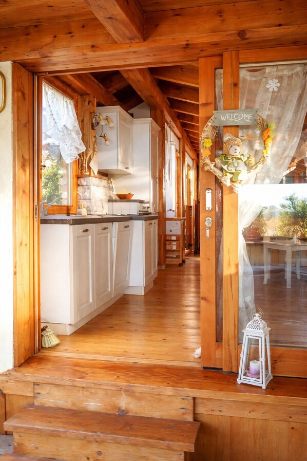 L’intérieur d’un chalet en bois comprend un coin cuisine, un escalier en bois et offre une vue sur l’extérieur.