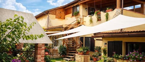 Una casa de dos pisos con escalera de madera, mobiliario exterior y plantas en macetas.
