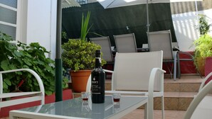 An outdoor patio with a table, chairs, a bottle of wine, and two shot glasses. - Mira Porto House Cellars (Porto)