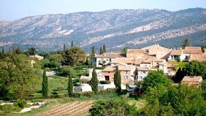 Ein Dorf mit traditioneller Architektur, terrassenförmigen Feldern und Bergen im Hintergrund.