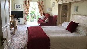 Una habitación de hotel con cama, escritorio con silla, sillón rojo y televisor.