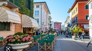 A street with outdoor seating, a flower bed, and buildings with balconies. - Italy, Tuscany, Versilia, Cinquale 400 meters from the sea and 3km from Forte dei Marmi (Capanne-Prato-Cinquale)