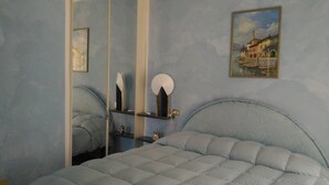 A bedroom with a bed, a bedside table, a mirror, and a painting on the wall. - Italy, Tuscany, Versilia, Cinquale 400 meters from the sea and 3km from Forte dei Marmi (Capanne-Prato-Cinquale)
