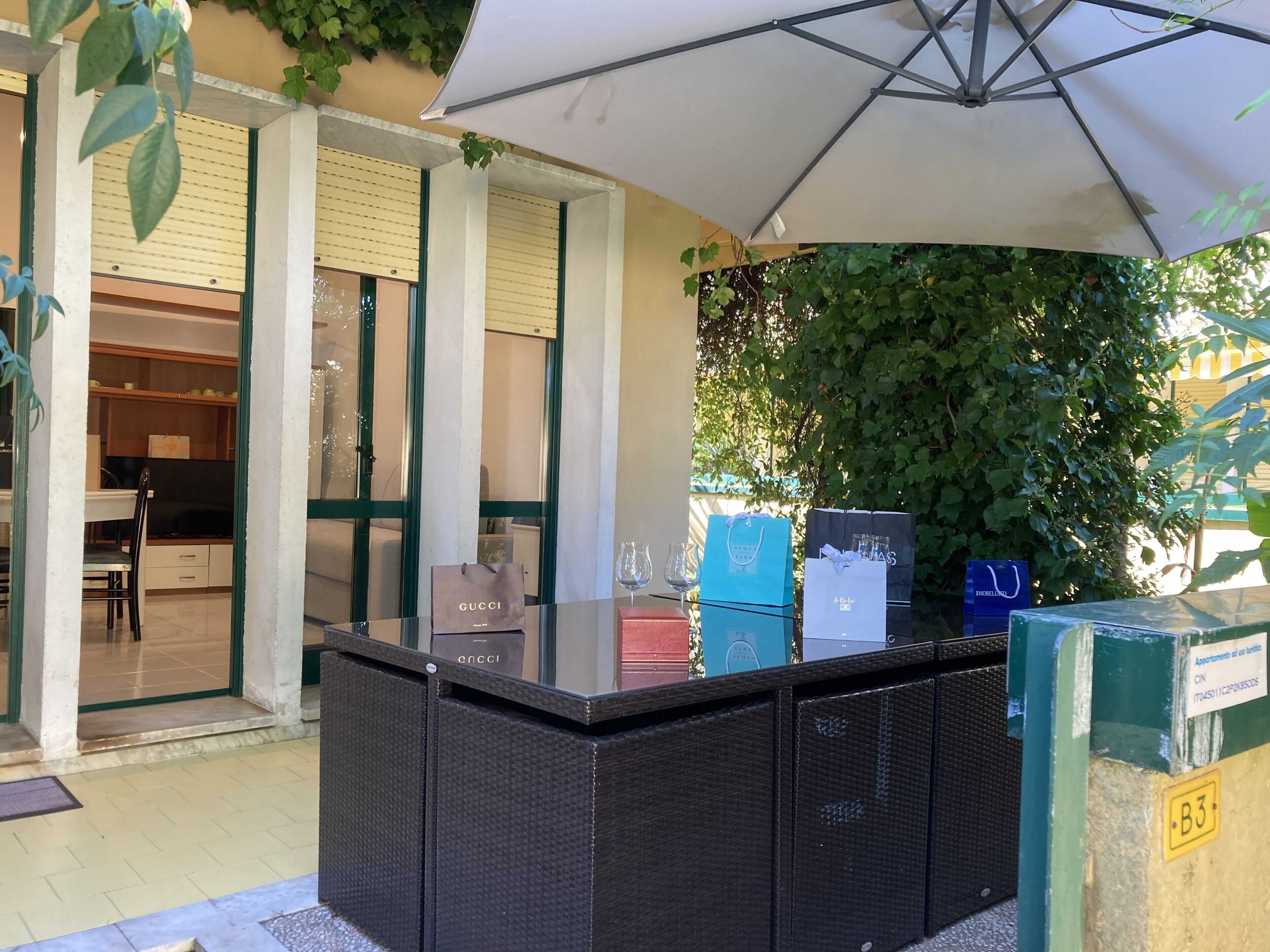 A bar area with a glass counter, a white umbrella, and a view of a building with a green door.