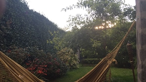 A hammock in a garden with a person lying in it.