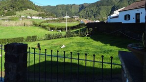 A rural landscape with a white building, green fields, and a stone wall.