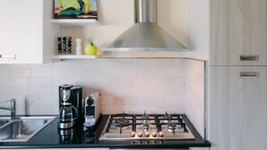 A modern kitchen with a gas stove, coffee maker, and a painting of lemons on the wall. -  LEMON IN THE AIR  (Pontone)