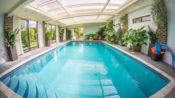 Swim laps in a large pool surrounded by lush greenery and a glass ceiling.