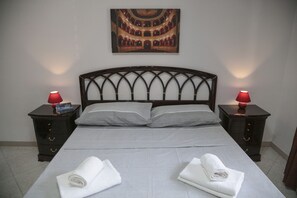 A neatly made bed with two pillows, two bedside tables with lamps, and a painting on the wall.