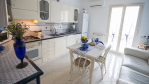 Une cuisine moderne avec des meubles blancs, une table à manger avec des chaises et un canapé dans le salon attenant.