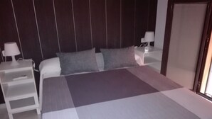 Una cama bien hecha con un edredón a rayas, dos almohadas y una mesita de noche con una lámpara.