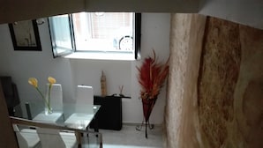 Un comedor con una mesa de vidrio, sillas, mantel negro, planta decorativa y una maqueta de una famosa torre.