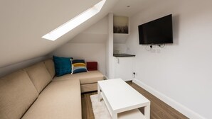Un salon moderne avec un canapé, une table basse blanche et un téléviseur à écran plat fixé au mur.